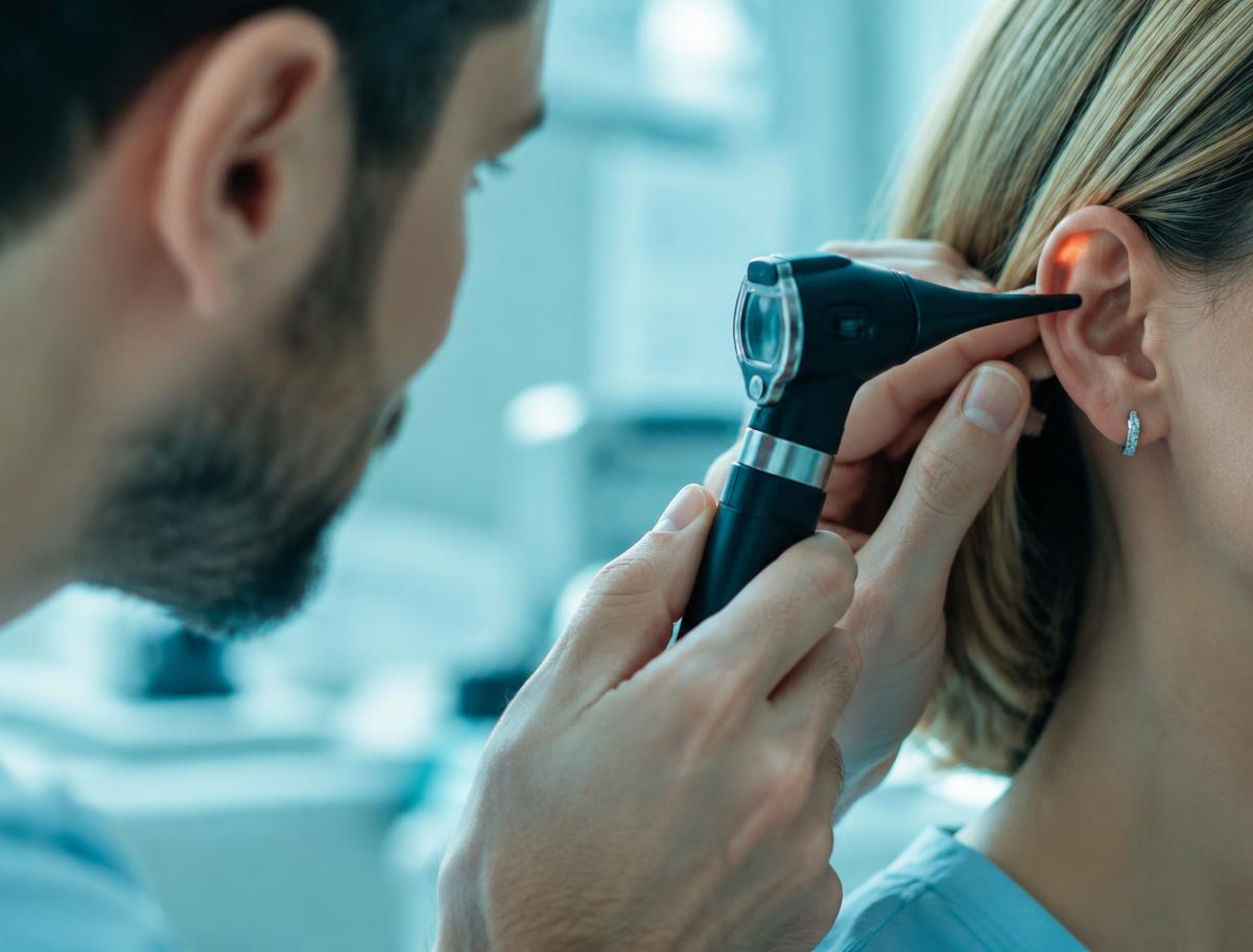 Médico examinando o ouvido de uma paciente com otoscópio